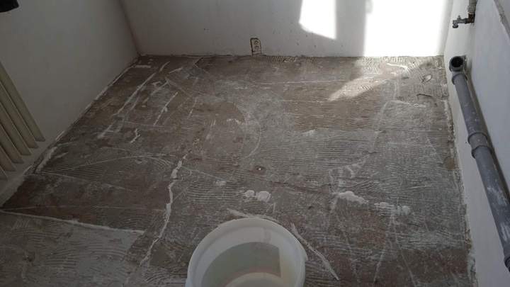 Podlaha koupelny po odstranění staré dlažby, na betonu zbytky lepidla
